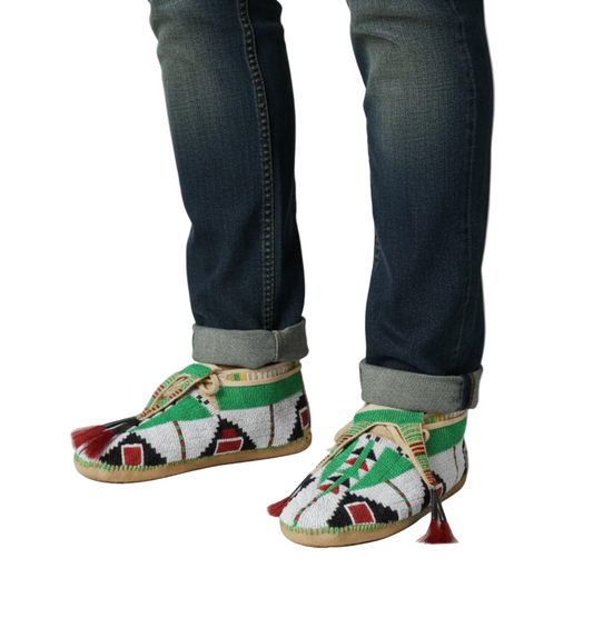Pair of handcrafted moccasins with intricate patterns on a wooden floor.